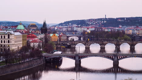 prague nightfall timelapse, turning on street lamps over famous bridges, zoom out view