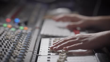 close up shot of the musician's hands, the professional records the music in the sound recording studio, the man moves the sliders on the mixer