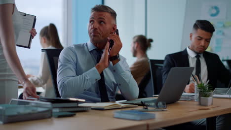 hombre de negocios sonriente hablando en teléfono inteligente en la oficina