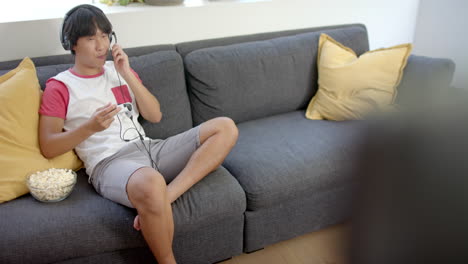 adolescente asiático disfruta de la música en el sofá en casa con espacio para copiar