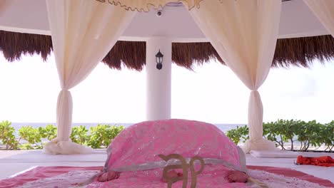 an approaching shot of a sikh alter decorated with white and pink curtains that are blowing in the wind