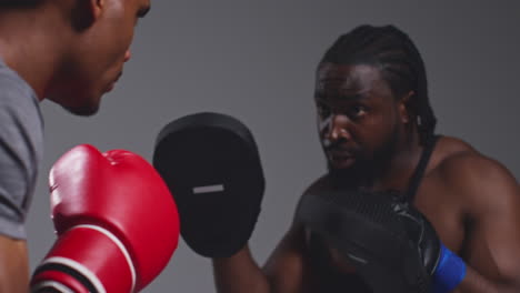 toma de cerca de un boxeador masculino luchando con un entrenador que lleva guantes o guantes de puñetazos practicando para la pelea 5