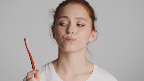 redheaded girl in front of camera on gray background.