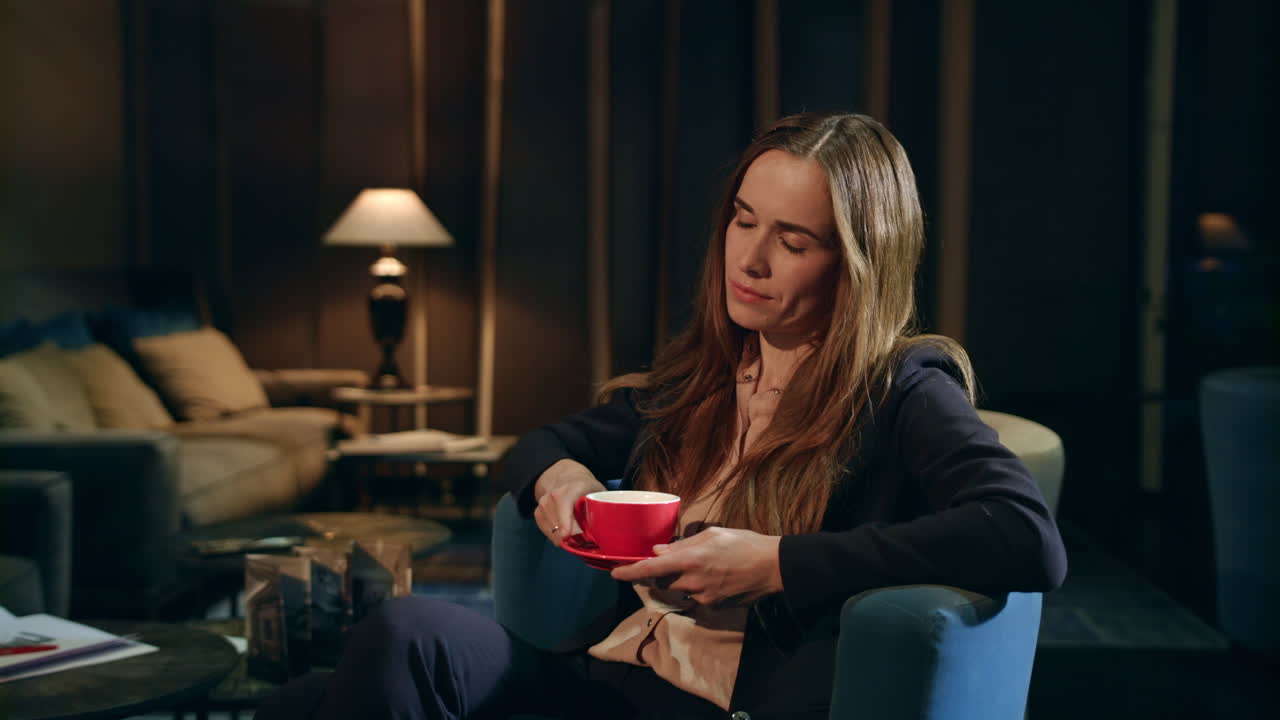 Træt forretningskvinde drikker te i hotellobby om aftenen. Udmattet kvinde.