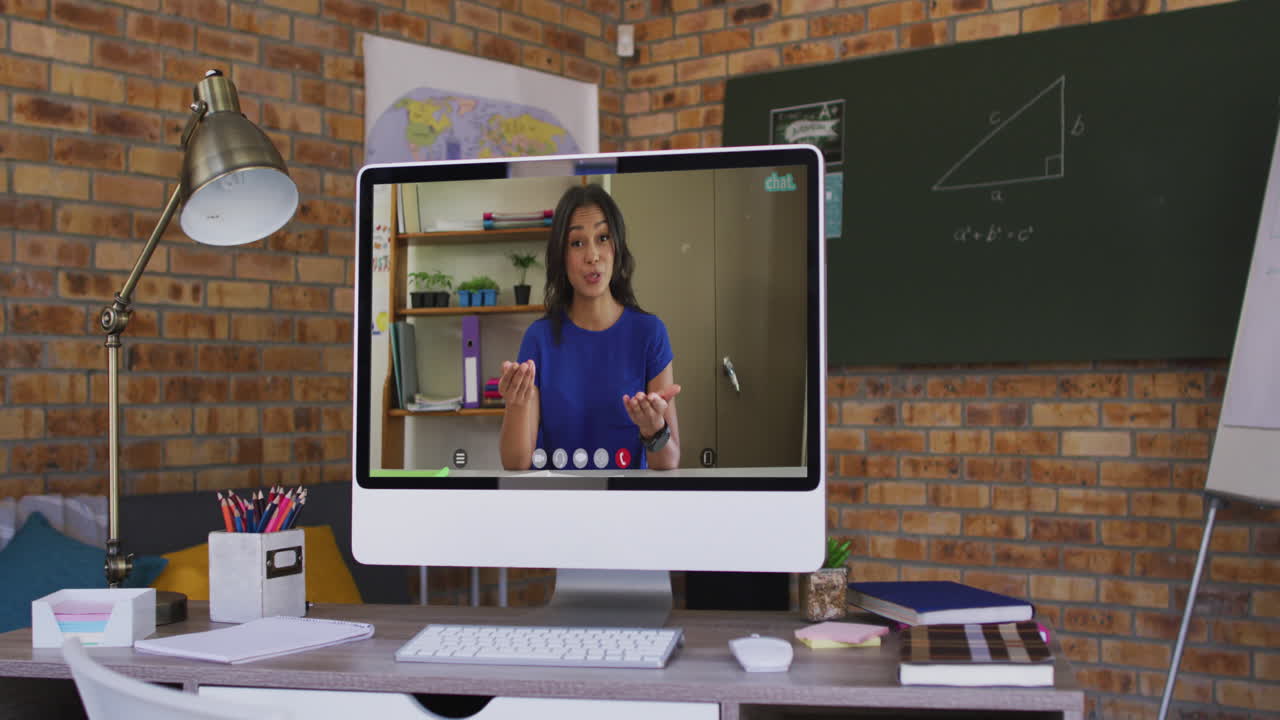 mujer biracial haciendo una llamada de video de negocios en la pantalla de la computadora en el escritorio