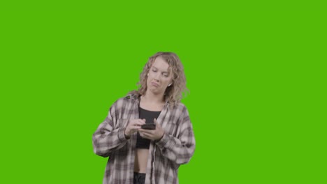 Studio-Shot-Of-Young-Woman-Listening-To-Music-On-Mobile-Phone-And-Dancing-Against-Green-Screen-1