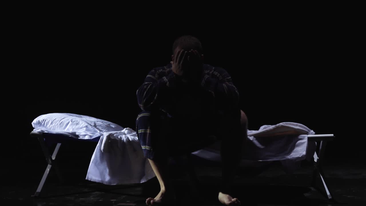 Man Sitting on a Bed at Night