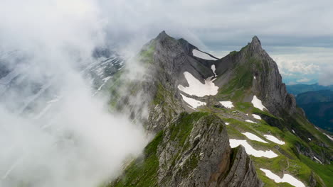 Cinematic-rotating-drone-shot-of-Altenalp-Turm,-with-clouds-on-one-side-of-the-mountain