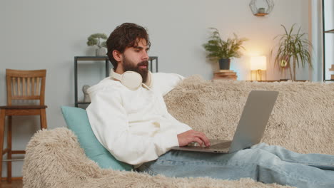 confident young man on sofa couch using laptop making an online video conference call at distance