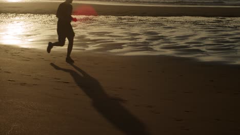 silhouette and shadow of man running on the beach at sunset with