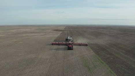 Un-Tractor-Sembrador-Sembrando-En-Las-Tierras-De-Cultivo-En-Corriente-Rápida,-Saskatchewan,-Canadá---Disparo-De-Dron-Ascendente