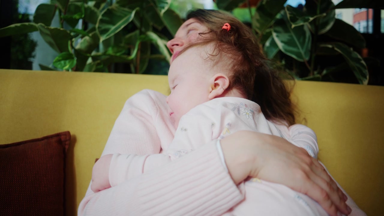 Una madre culla e tiene stretto il suo bambino, accarezzandogli delicatamente la schiena in un tenero momento di cura.