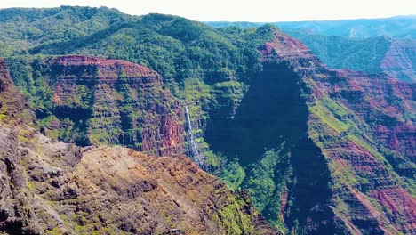 Hd-Hawaii-Kauai-Zeitlupe-Statische-Breite-Aufnahme-Der-Waimea-schlucht-Mit-Einem-Hubschrauber,-Der-In-Den-Rahmen-Rechts-Eindringt-Und-Auf-Einen-Wasserfall-In-Der-Ferne-Zufliegt