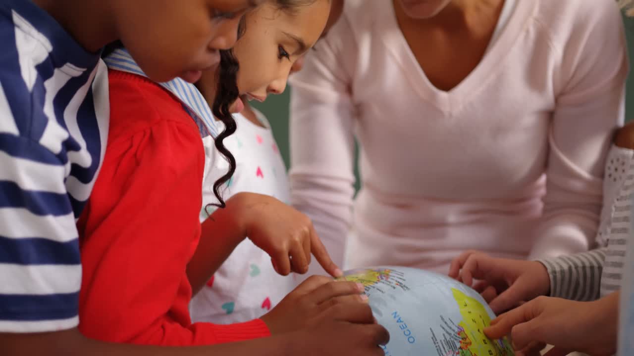 vista frontal de la maestra caucásica explicando sobre el globo en el aula 4k