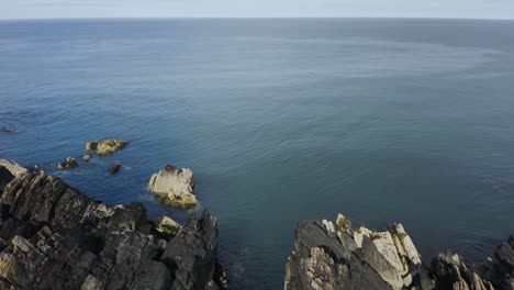 Drone-Está-Volando-Hacia-El-Mar-A-Lo-Largo-De-La-Costa-Rocosa-De-Clogherhead,-Irlanda