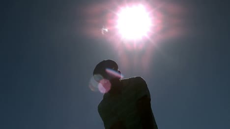 golfer taking a swing under the sun