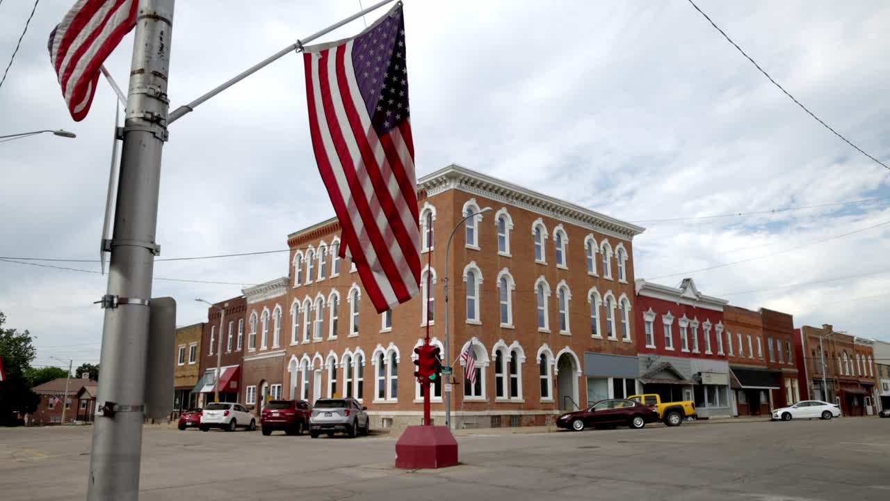 Antikt firevejs-stoplys og amerikansk flag i centrum af Toledo, Iowa med et stabilt videonærbillede i skrå vinkel.
