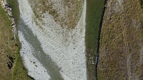 aerial view above clear braided river with four wheel drive track next to the river
