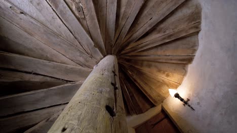 slow upward shot revealing an ancient wooden spiral staircase in a chateau