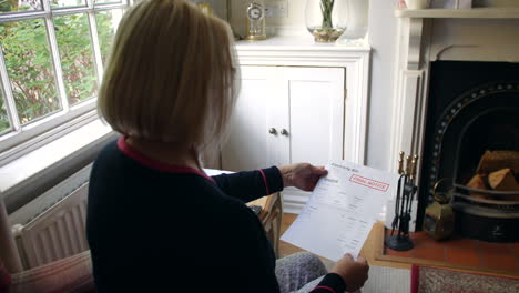 una anciana irreconocible preocupada por las deudas abriendo una carta de deuda