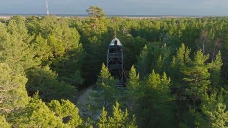 Luftaufnahme-Eines-Modernen,-Bootförmigen-Aussichtsturms-Mitten-Im-Kiefernwald,-Nordischer-Wald,-Waldweg,-Sonniger-Abend,-Goldenes-Stundenlicht,-Drohnenaufnahme-In-Bewegung