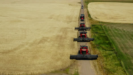 combine harvesters driving in the dirt road to harvest crops in the field