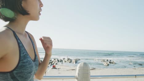 happy biracial woman running on promenade by beach, in slow motion