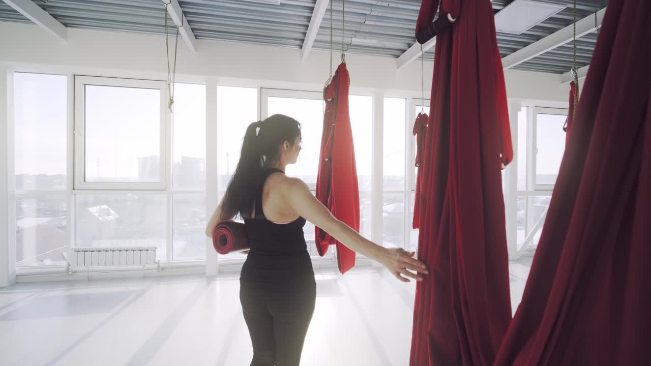 Woman practicing yoga in a studio with aerial yoga equipment