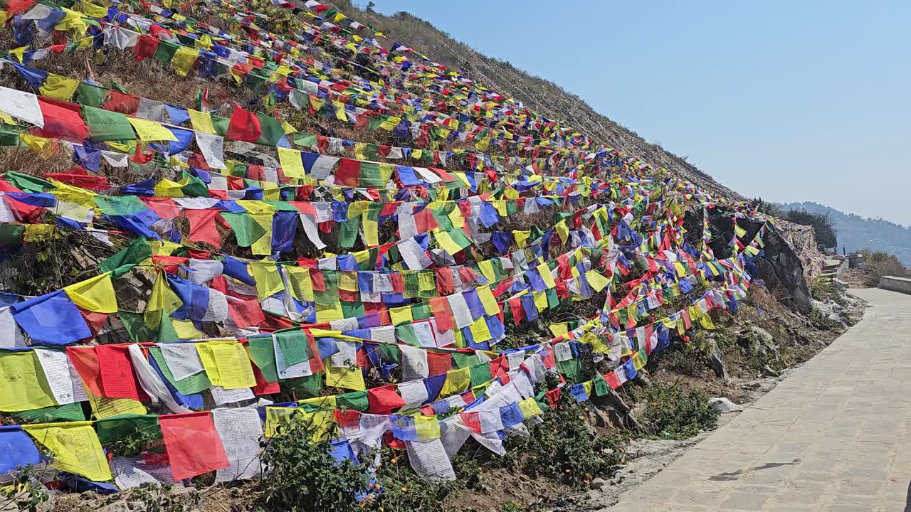 Vibrant prayer flags spread across a rocky hillside near Muktinath in Mustang, Nepal, symbolizing peace and spiritual devotion under the clear blue Himalayan sky