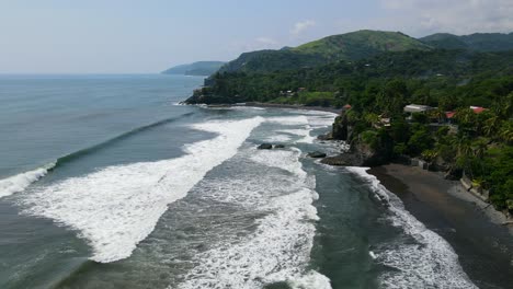 Aerial-view-moving-left-shot,-scenic-view-of-the-bitcoin-beach-on-a-bright-sunny-day-in-El-Salvador,-Mexico,-mountain-and-a-blue-sky-in-the-background