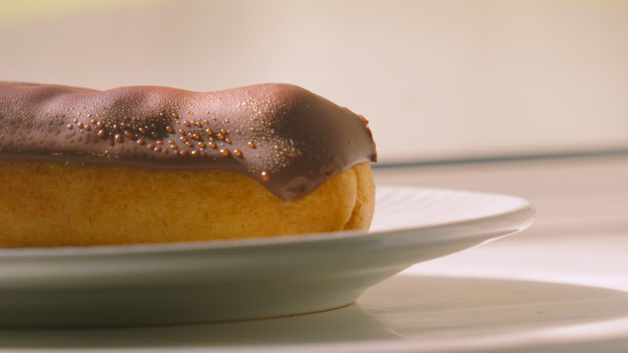 Naturally Lit Medium Pan Across Eclair Topped with Chocolate and Puff Pastry Filled with Whipped Cream. Traditional French Dessert Ready to Eat and Enjoy. Food Photography.