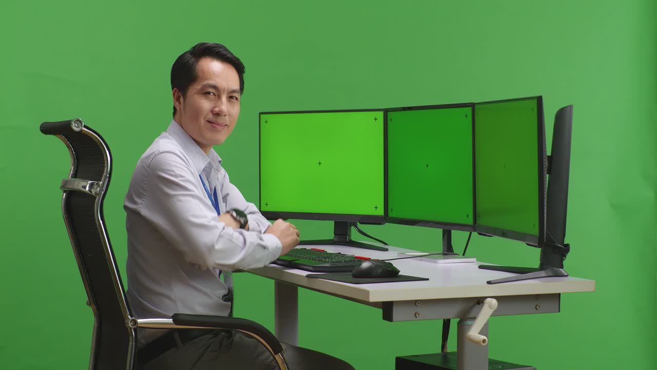 여러 모니터 를 가진 컴퓨터 에 앉아 있는 사람