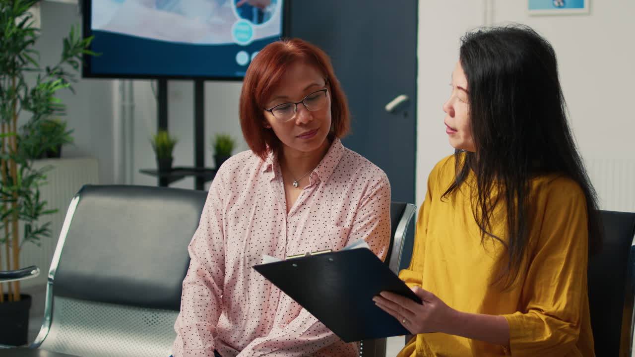 Asian woman in hospital waiting room with doctor