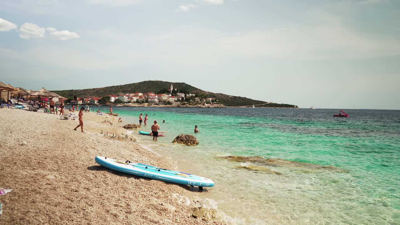 Primosten Croatia July 30, 2024, Idyllic Beach on Mediterranean Sea Coast Near Medieval Primosten City in Croatia. Summer Holidays Travel Destination Tourists Sunbathing and Enjoying Mala Raduca Beach