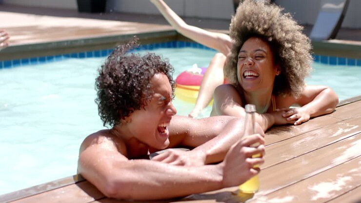 Laughing and relaxing in pool, Diverse friends enjoying summer day with drinks