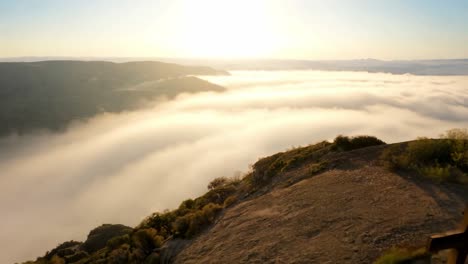 golden light of the sun rising above a sea of clouds in a mountain valley with a cross in the foreground