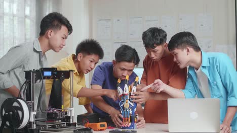 group of young asian boys with a laptop and 3d printing helping each other repairing a cyborg hand at home