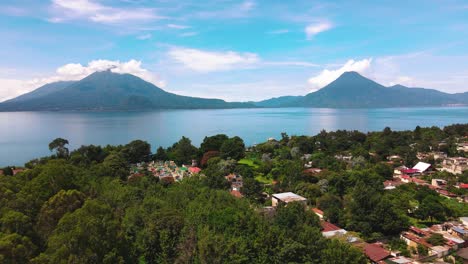 aerial flyover village toward lake and volcanoes - lake atitlan, panajachel, guatemala