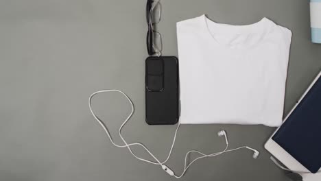 video of white t shirt, smartphone and earphones with copy space on grey background