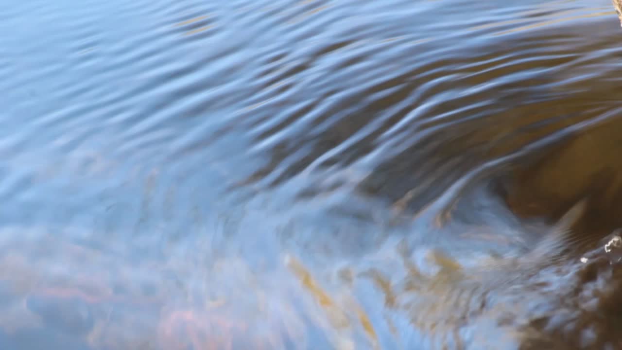 Diagonal clear water flow on a river with blue colors reflection