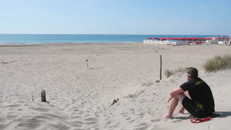 man playing with his dog on a sandy  beach sete france