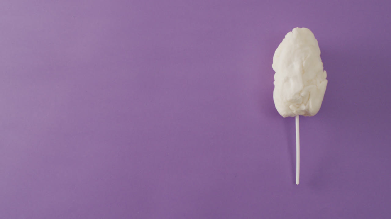 видео зефира на палке, лежащем на фиолетовой поверхности