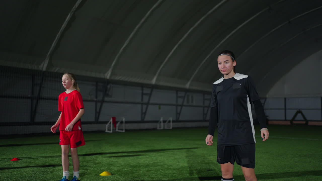 두 명의 어린 소녀가 실내에서 축구를 하고 있습니다.