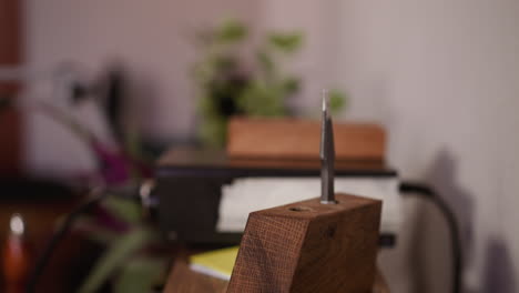 worker takes leather cutter from wooden rack in craft shop