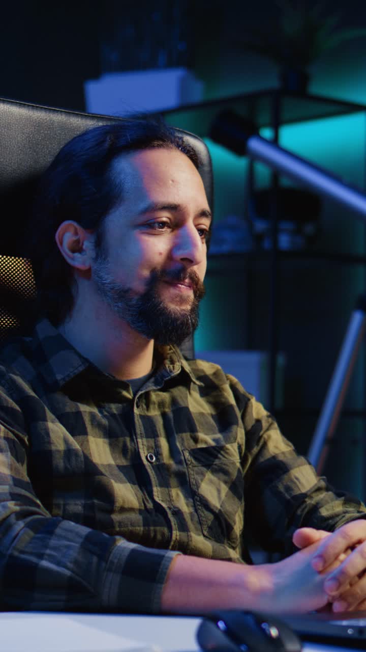 Vertical video Smiling man relaxing in living room by watching funny internet clips on laptop