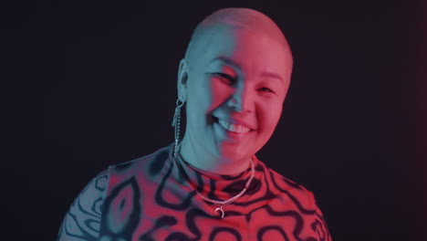 portrait of a smiling bald woman in neon light