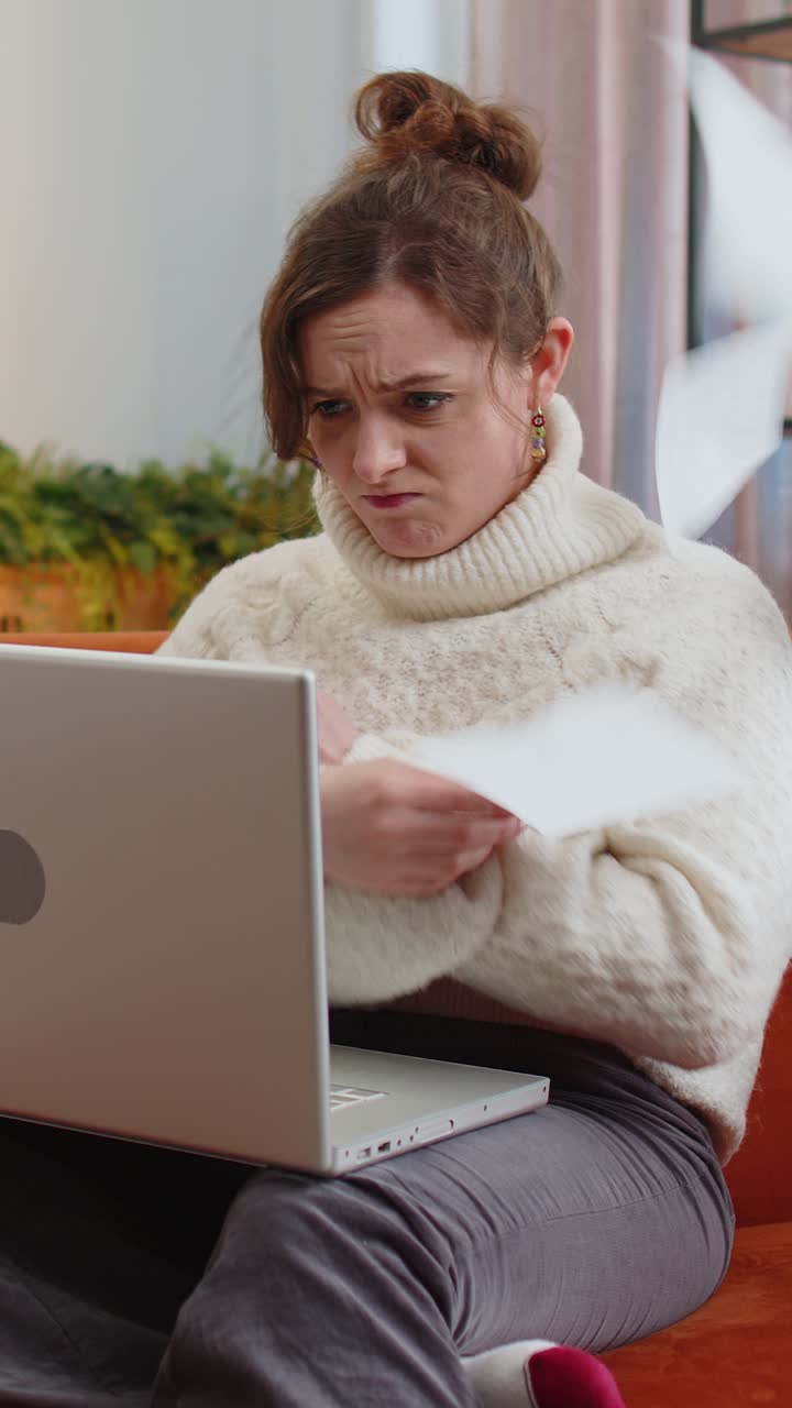 Stressed young woman looking at unpaid bank debt loan doing paperwork planning budget throws bills