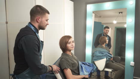 young woman with hairdresser cutting hair at salon