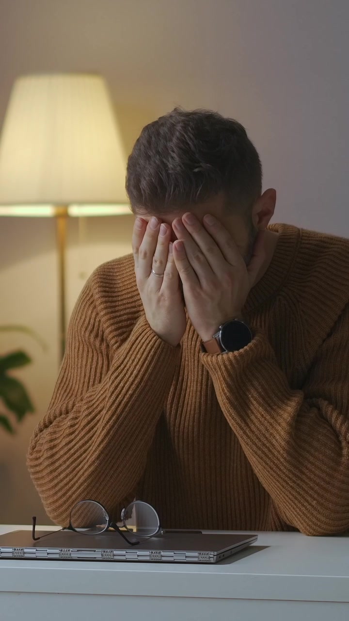 Uomo stanco che chiude il portatile, si toglie gli occhiali e si strofina gli occhi