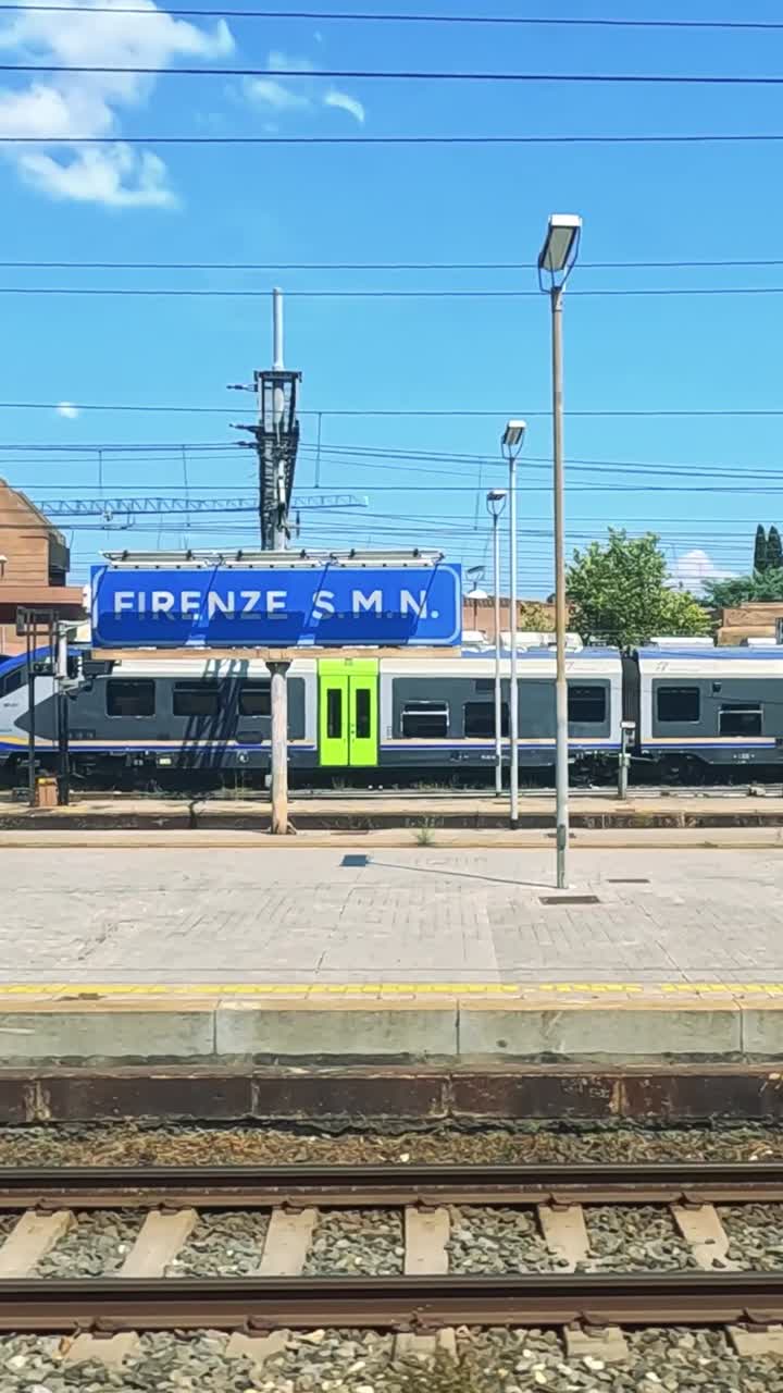 Et tog kører gennem en solrig Napoli-station